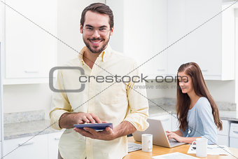 Young man smiling at camera holding tablet pc