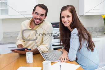 Young couple smiling at camera using technology