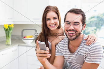Young couple smiling at the camera man holding smartphone