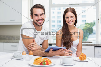 Young couple using tablet at breakfast