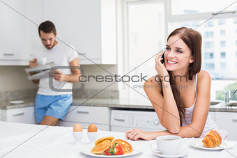Young woman talking on phone at breakfast