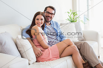 Young couple smiling at camera on couch