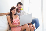 Hipster couple using laptop on couch