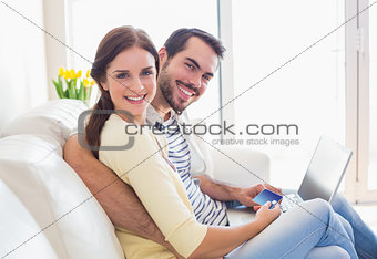 Cute couple relaxing on couch with laptop
