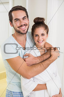 Young couple hugging and smiling at camera