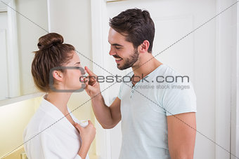 Young man putting cream on girlfriends nose