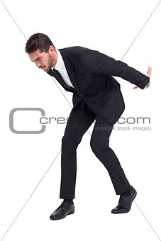 Businessman carrying something heavy with his back and hands