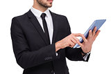 Mid section of a businessman using digital tablet pc