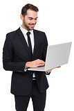 Smiling businessman standing and using laptop