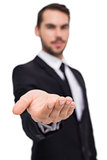 Cheerful businessman offering with his open hand