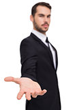 Smiling businessman offering something with his open hand