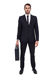Serious businessman posing and holding briefcase