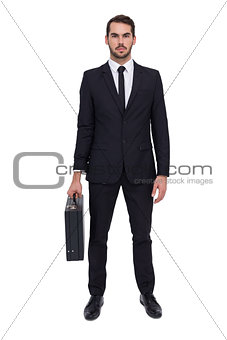 Serious businessman posing and holding briefcase