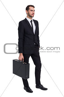Cheerful businessman holding briefcase while hand in pocket