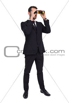 Elegant businessman standing and using binoculars