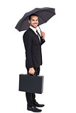 Smiling businessman under umbrella with a briefcase