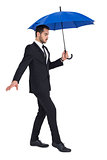 Concentrated businessman holding umbrella while stepping