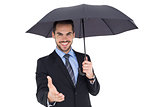 Happy businessman under umbrella offering handshake