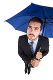 Anxious businessman under umbrella looking up