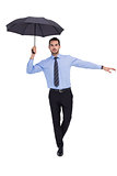 Focused businessman with umbrella balancing