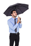 Anxious businessman sheltering with umbrella