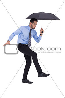 Focused businessman holding umbrella and balancing