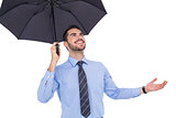 Happy businessman sheltering with a black umbrella