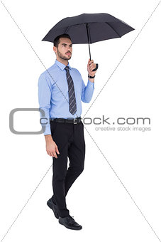 Serious businessman standing under umbrella