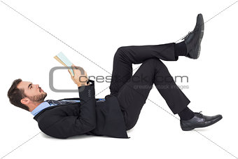 Businessman lying on the floor while reading a book