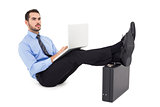 Businessman sitting on the floor with feet up on suitcase