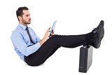 Businessman sitting using tablet with feet on his briefcase