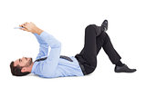Cheerful businessman lying on floor using tablet