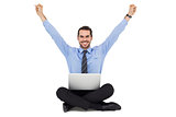 Smiling businessman sitting on the floor cheering