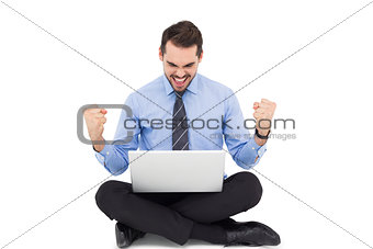 Businessman sitting with his laptop cheering