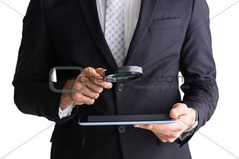 Businessman using magnifying glass and tablet