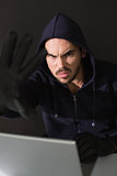 Hacker sitting at desk hacking a laptop