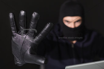 Hacker in balaclava with fingers spread out