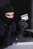 Hacker in balaclava spending money online