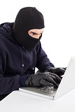 Focused hacker in balaclava hacking laptop