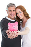 Casual couple showing their piggy bank