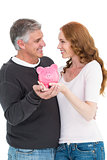 Casual couple showing their piggy bank