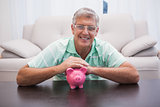 Smiling mature man with piggy bank