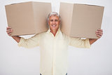 Smiling man balancing heavy cardboard boxes