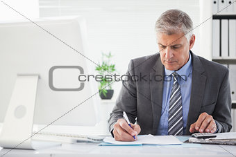 Focused businessman writing something down