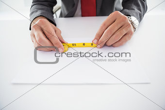 Businessman using measuring tape at desk