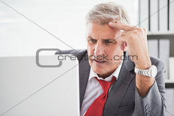 Confused businessman looking at his laptop