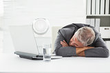 Mature businessman sleeping on desk