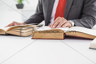 Businessman sitting at desk reading books