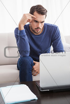 Serious young man using his laptop