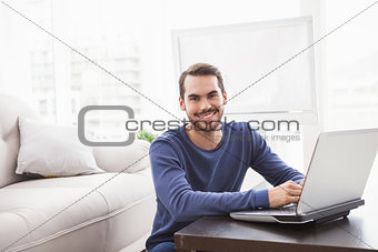 Smiling young man using his laptop